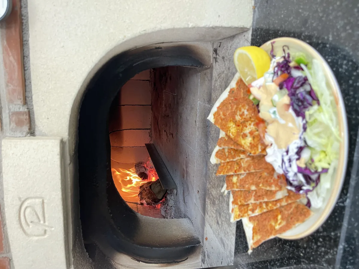Frischer Lahmacun mit Beilagensalat und Zitrone vor dem Holzofen