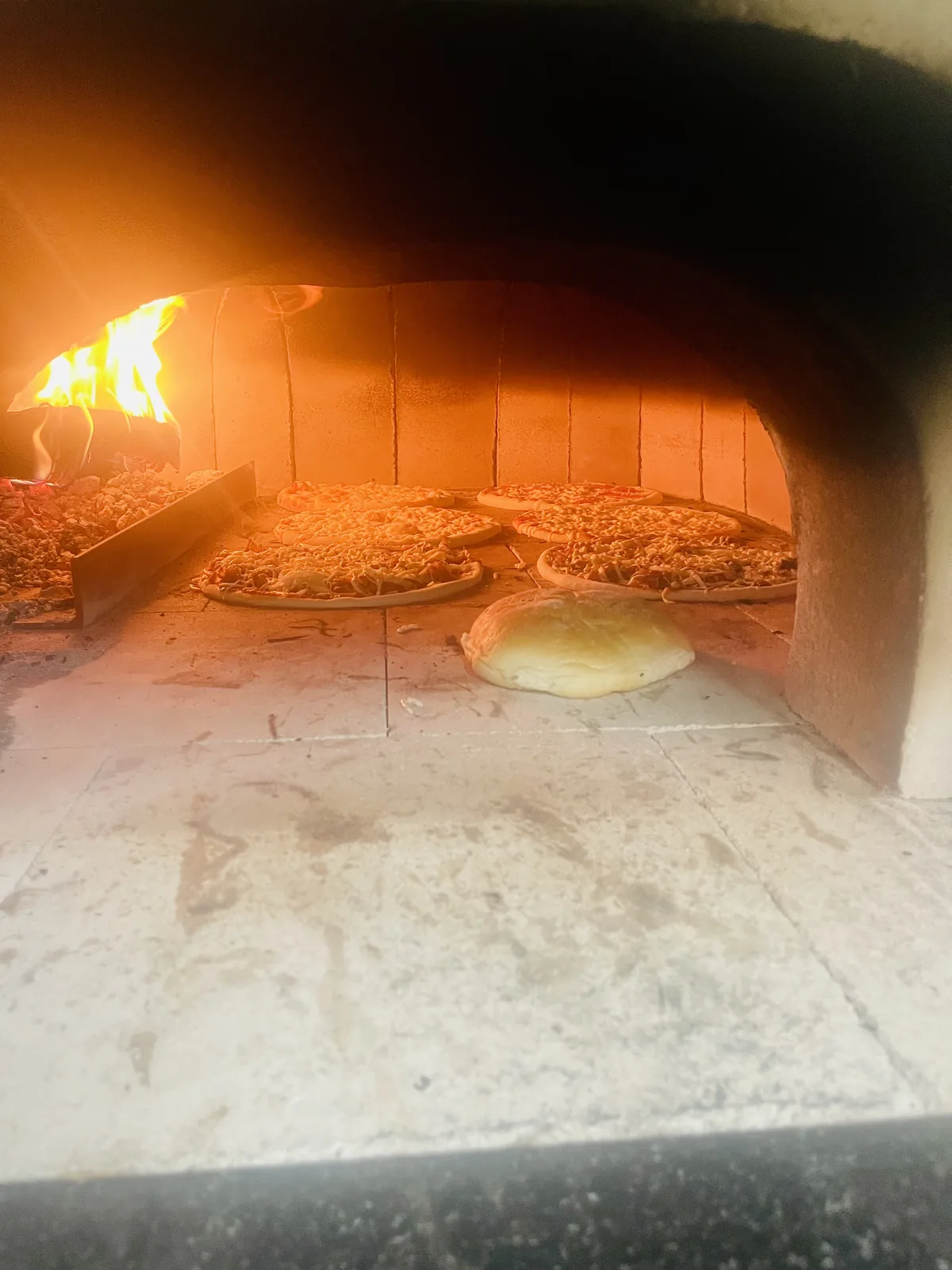 Holzofenbackofen mit mehreren Pizzen und Brot – authentische Zubereitung
